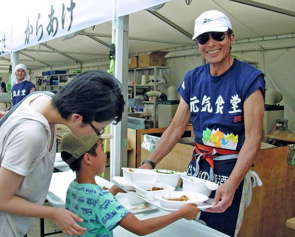 　男の子に食事を渡す舘ひろし＝熊本県益城町