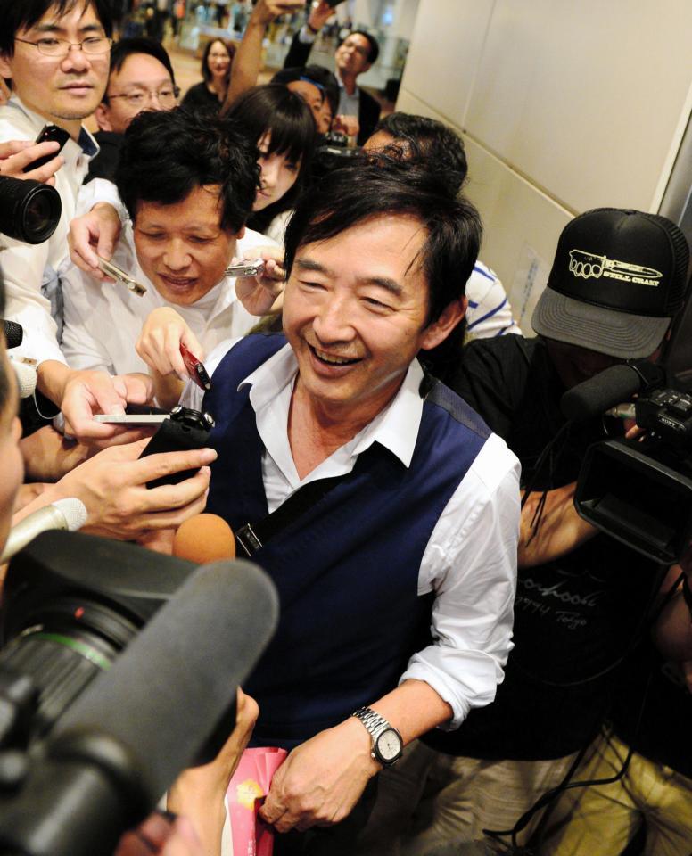 報道陣にもみくちゃにされ苦笑いする石田純一＝羽田空港（撮影・三好信也）