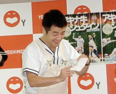 「改名」の札を見ながら苦笑いする和牛の水田信二＝大阪市の吉本興業本社