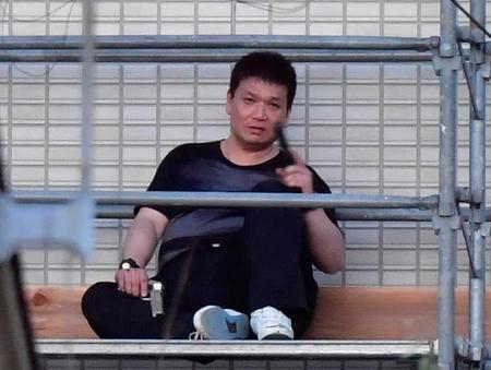 　逃げ込んだ建物の足場に座り込み、拳銃を手にする溝畑泰秀容疑者＝３１日午前５時１０分、和歌山市