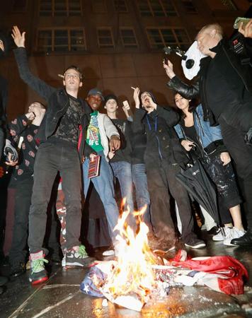 　ニューヨークのトランプタワー前で、トランプ氏に抗議し、星条旗に火を付けるデモ隊