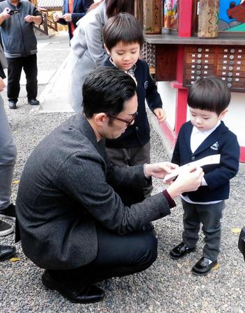 息子の哲之（右）、七緒八（中央）におみくじの説明をする中村勘九郎＝岡山・吉備津神社