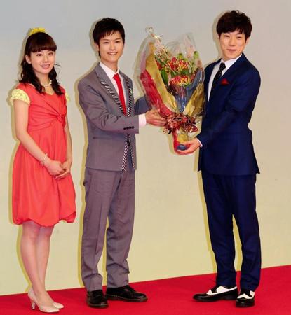 「おかあさんといっしょ」を卒業する横山だいすけ（右）に花束を渡す新お兄さんの花田ゆういちろう（中央）。左はうたのお姉さんの小野あつこ。