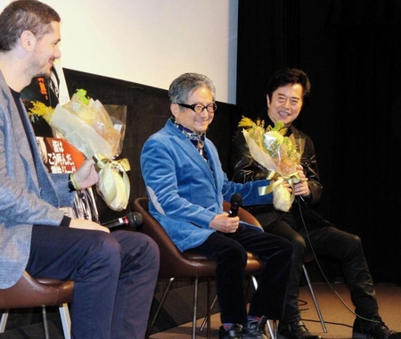 水木一郎（右）から「鋼鉄ジーグ」のカラーをイメージした花束を手渡され笑顔のマイネッティ監督（左）と永井豪氏