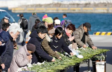 　福島県いわき市の豊間漁港で行われた法要で、献花し手を合わせる参列者　