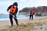 　岩手県宮古市田老の砂浜で行方不明者の手掛かりを求め、捜索するボランティアの大学生　