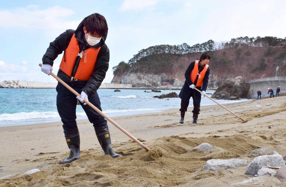　岩手県宮古市田老の砂浜で行方不明者の手掛かりを求め、捜索するボランティアの大学生　