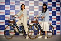 自転車に乗って登場した吉田羊（左）と小松菜奈＝東京・虎ノ門