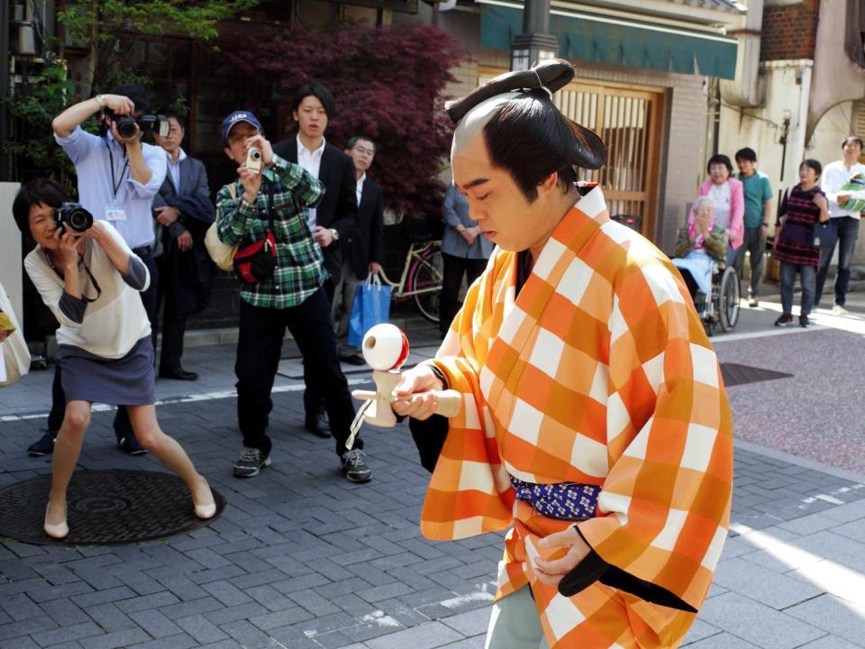 　けん玉で「もしもしかめよ」をしながら歩く三山ひろし＝東京・北品川