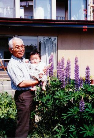 孫を抱っこする荒木良治さん。山形県の自宅前で＝１９９０年撮影
