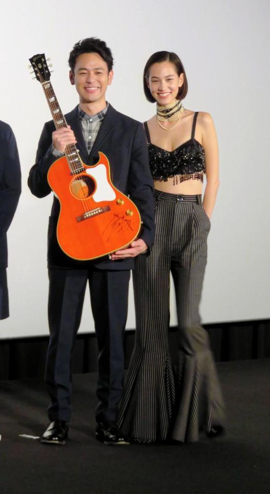 奥田民生のサイン入りギターを贈られ喜ぶ妻夫木聡（左）と共演の水原希子＝東京・六本木