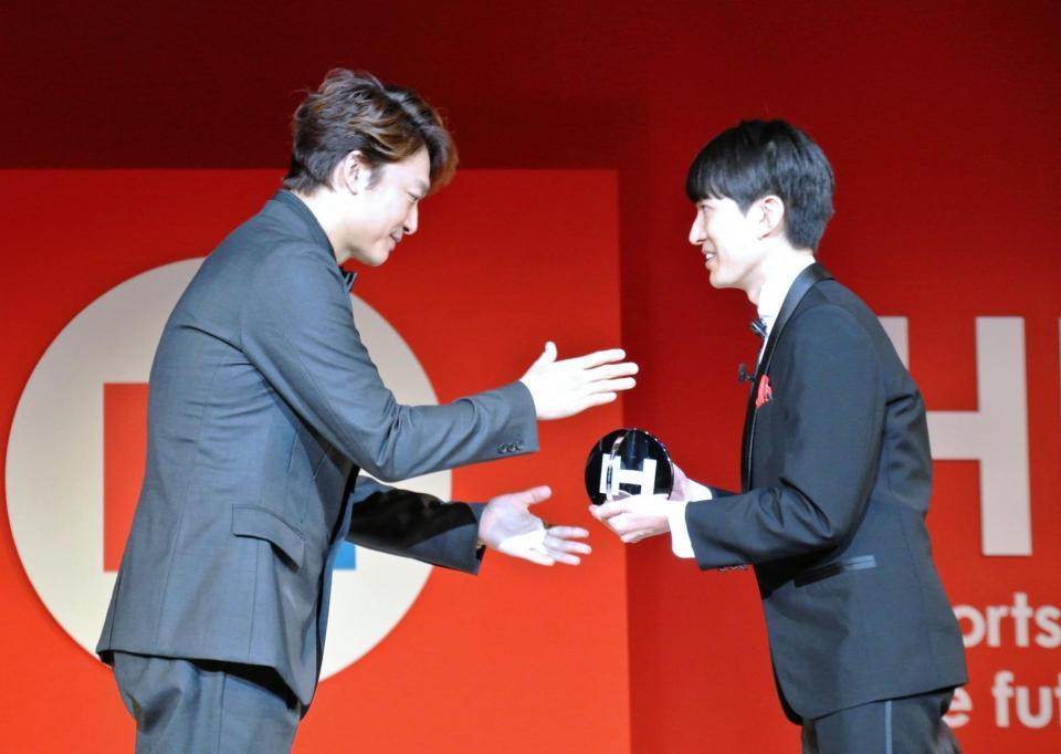 受賞者にトロフィーを手渡す香取慎吾（左）＝東京・六本木