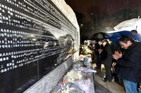 　犠牲者の名前が刻まれた慰霊碑前で手を合わせる人たち＝兵庫県西宮市　