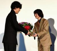 サプライズゲストで登場したＲＡＤＷＩＭＰＳの野田洋次郎は染谷将太に花束を贈る＝ＴＯＨＯシネマズ六本木（撮影・三好信也）
