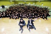 母校・因島高校の卒業式イベントにサプライズ登場し、後輩たちと記念撮影するポルノグラフィティの岡野昭仁（右）と新藤晴一＝広島・尾道市