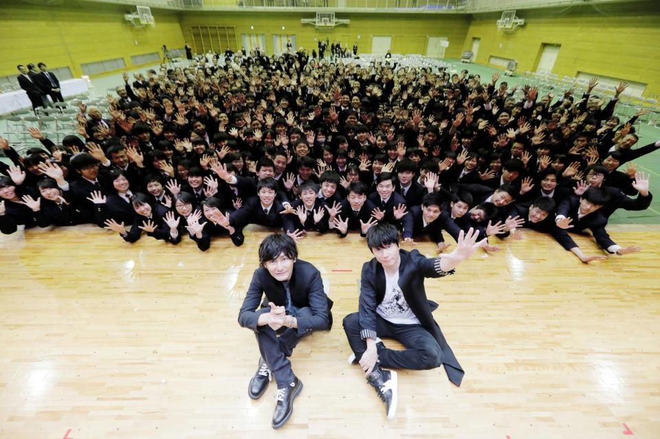 母校・因島高校の卒業式イベントにサプライズ登場し、後輩たちと記念撮影するポルノグラフィティの岡野昭仁（右）と新藤晴一＝広島・尾道市