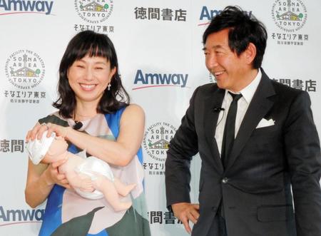 防災グッズのおむつを人形に履かせ、満足する石田純一（右）と東尾理子＝都内・アムウェイプラザ