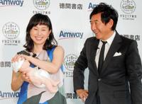 防災グッズのおむつを人形に履かせ、満足する石田純一（右）と東尾理子＝都内・アムウェイプラザ