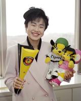 　デイリースポーツのインタビューに応じ、阪神グッズを手に笑顔を見せる＝１９９４年