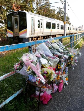 　大桃珠生さんの遺体発見から１週間となり、現場付近に設けられた献花台に手向けられた花束やジュース。奥はＪＲ越後線＝１４日午後、新潟市