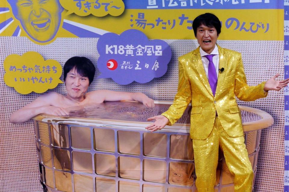 黄金風呂のパネルと並ぶ千原ジュニア＝東京・赤坂