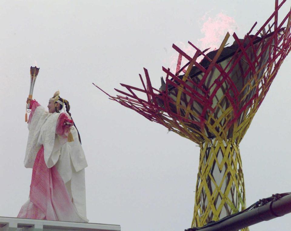 　長野五輪開会式で巫女（みこ）をイメージした衣装の伊藤みどりさんの手によって、かがり火をモチーフにした聖火台に点火された聖火＝１９９８年２月７日
