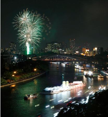 奉納花火が夜空を染める大川を、船が行き交う天神祭の「船渡御」＝25日夜、大阪市
