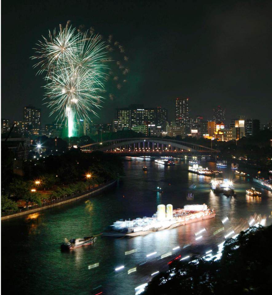 奉納花火が夜空を染める大川を、船が行き交う天神祭の「船渡御」＝25日夜、大阪市