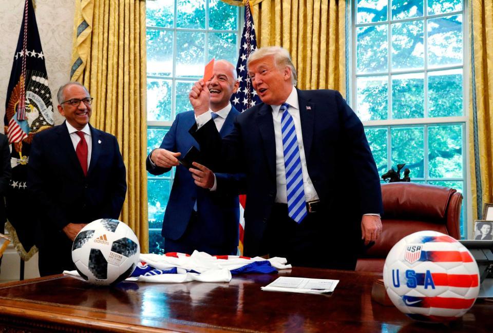 執務室でレッドカードを示すトランプ米大統領（右）とＦＩＦＡのインファンティノ会長（中央）＝ワシントン（ロイター＝共同）　