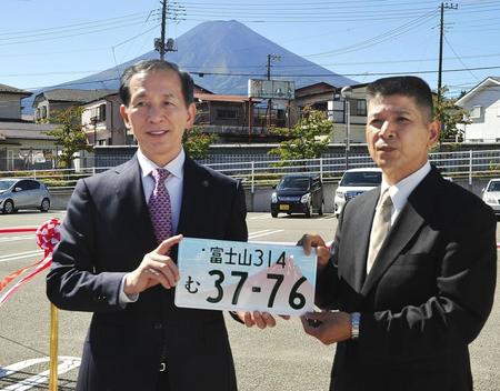 　山梨県富士吉田市で「富士山」ナンバーを手にする堀内茂市長（左）ら＝１日午前
