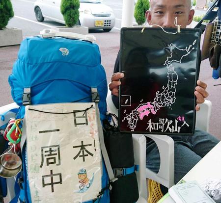 　山口県周防大島町の道の駅「サザンセトとうわ」で撮影に応じる樋田淳也容疑者。左のバッグには「日本一周中」と記された紙が付けられていた＝９月１８日　