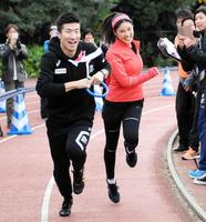 バトンパスをおこなう土屋太鳳（右）と桐生祥秀＝代々木公園陸上競技場（撮影・三好信也）