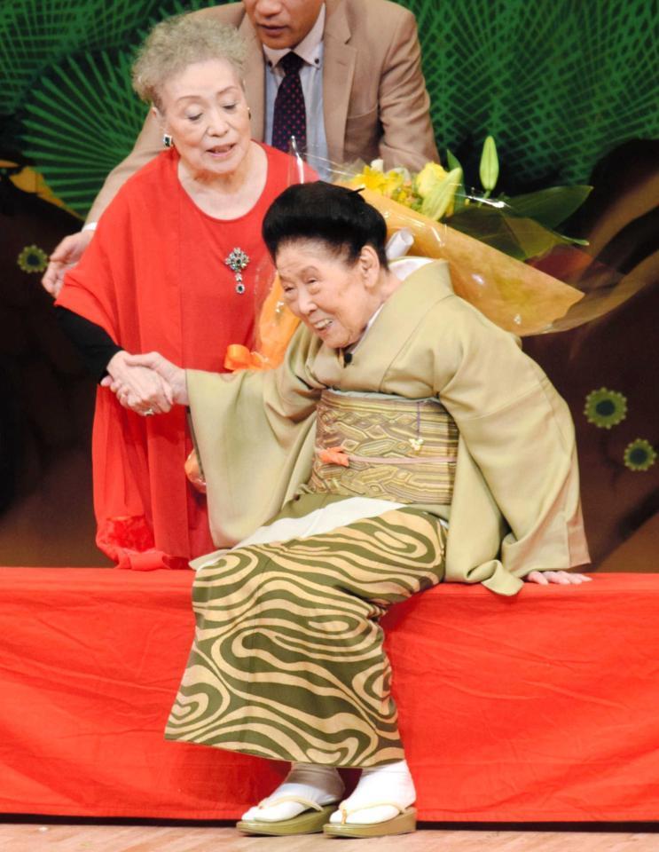 　友人の中村メイコ（左上）に花束を渡され喜ぶ内海桂子＝東京・浅草公会堂