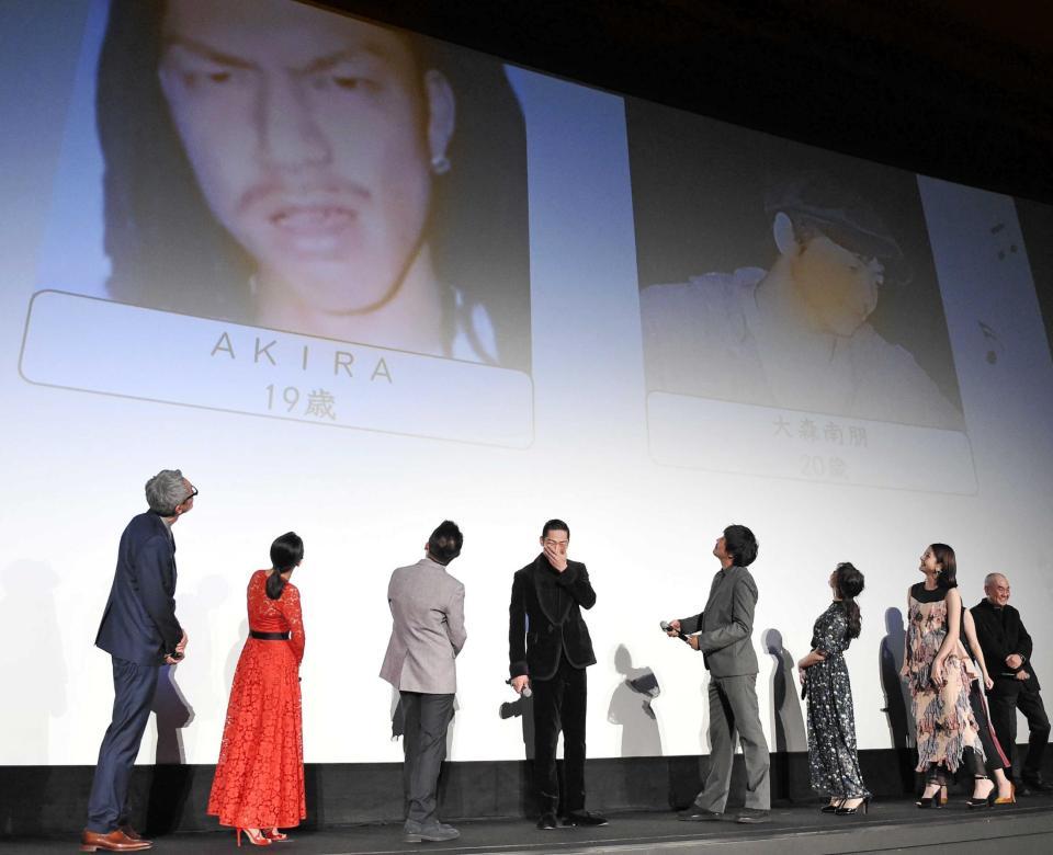 　１９歳の時の写真（スクリーン左）を公開され、苦笑いのＡＫＩＲＡ（中央）＝東京・ＴＯＨＯシネマズ日比谷（撮影・開出牧）