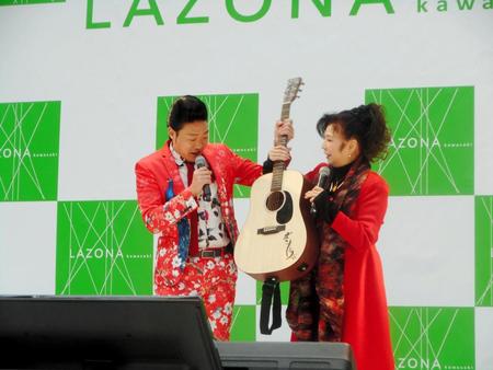 デュエット曲「だいじょうぶ」発売記念イベントで八代亜紀（右）からサプライズでギターを贈られたみやぞん＝神奈川・ラゾーナ川崎
