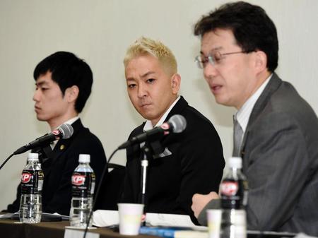 　記者会見で険しい表情の平尾勇気（中央）。右は鈴木繁伸公認会計士、左は東口良司弁護士