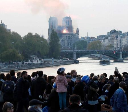　炎上するノートルダム寺院を見つめる人たち＝１５日、パリ（ロイター＝共同）