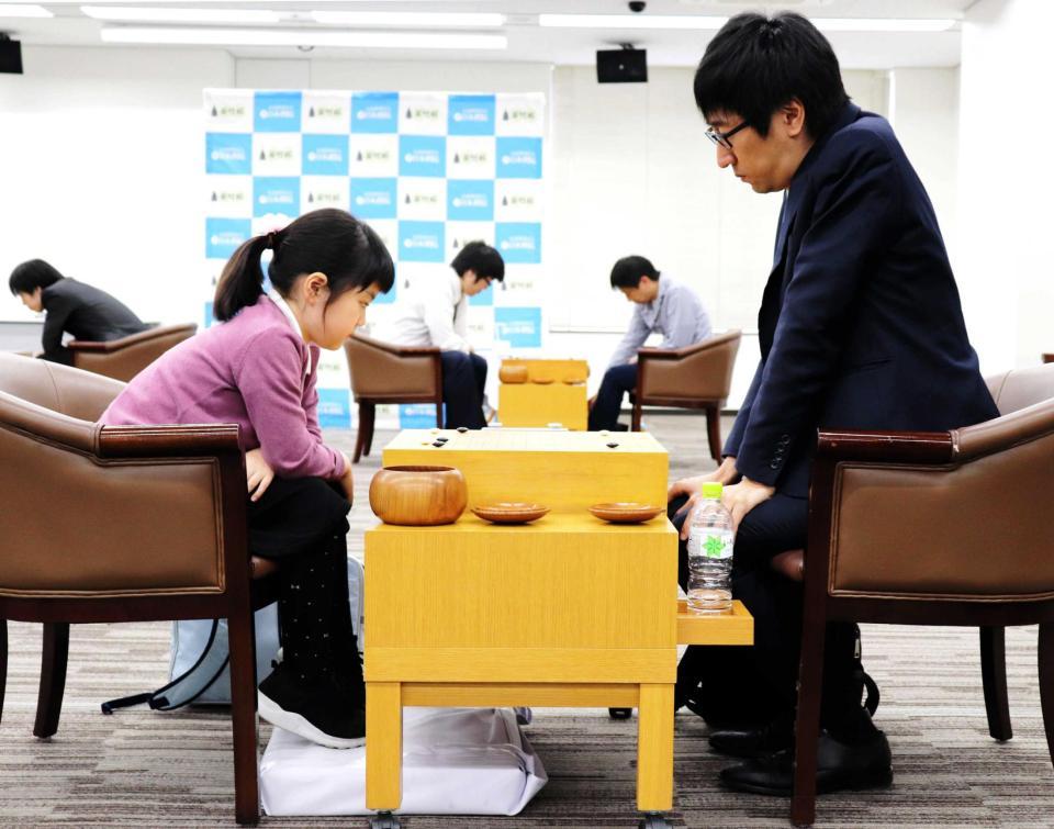 　兄弟子の村松大樹六段（右）と対局。足が届かないため、台を置き、つま先を立てて碁盤を見つめる