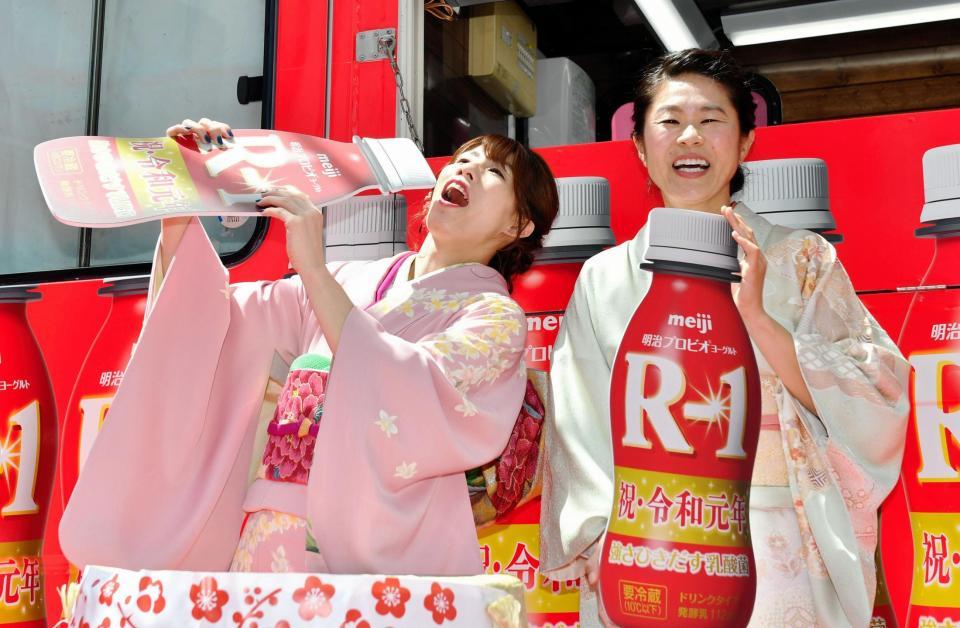 Ｒー１を豪快に飲むポーズの吉田沙保里（左）に笑顔を見せる澤穂希＝東京・渋谷１０９（撮影・西岡正）