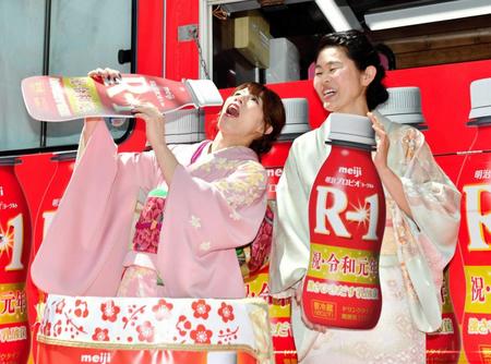　Ｒー１を豪快に飲むポーズの吉田沙保里さん（左）に笑顔を見せる澤穂希さん＝東京・渋谷１０９（撮影・西岡正）