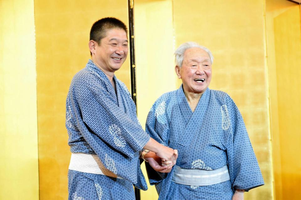 「落語協会　夏の寄り合い」で次男・三遊亭金時（左）と握手を交わす三遊亭金馬＝東京・浅草