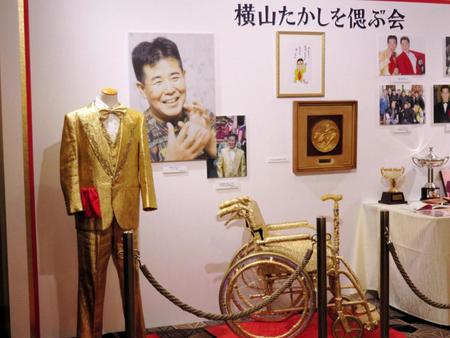 横山たかしさんを偲ぶ会の会場入り口には、金色のスーツ、金色の車イスと杖など、愛用の品々が飾られた＝大阪・リーガロイヤルホテル