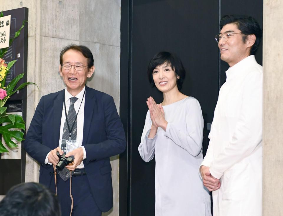 報道陣の写真を撮り喜ぶ（左から）周防正行監督と草刈民代、高嶋政宏＝都内