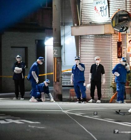 　発砲事件があった兵庫県尼崎市の現場付近を調べる警察官
