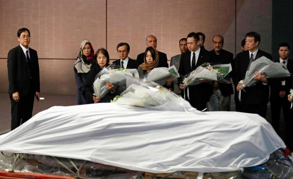　アフガニスタン東部で殺害された医師中村哲さんの遺体が納められたひつぎに花束を供える（前列左端から）妻尚子さん、長女秋子さんら＝成田空港