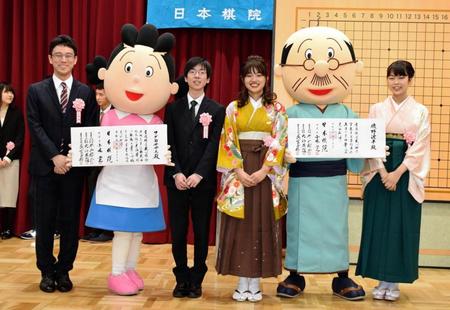 日本棋院からアマ五段の免状を受けたアニメ「サザエさん」のキャラ・磯野波平（左から４人目）、同三段の免状を受けたフグ田サザエ（同２人目）らと記念撮影する芝野虎丸二冠（同３人目）＝東京・日本棋院