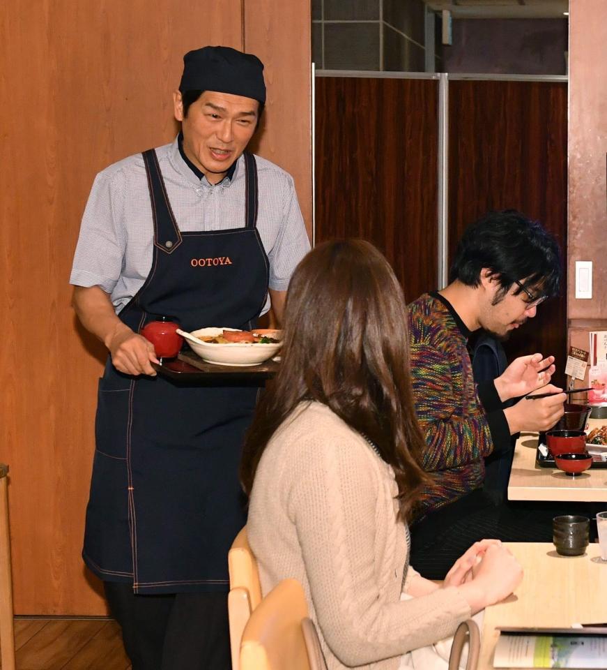 サプライズで一日店長を務め、女性客に定食を運ぶ高橋克典（左）＝東京・西新宿（撮影・西岡正）