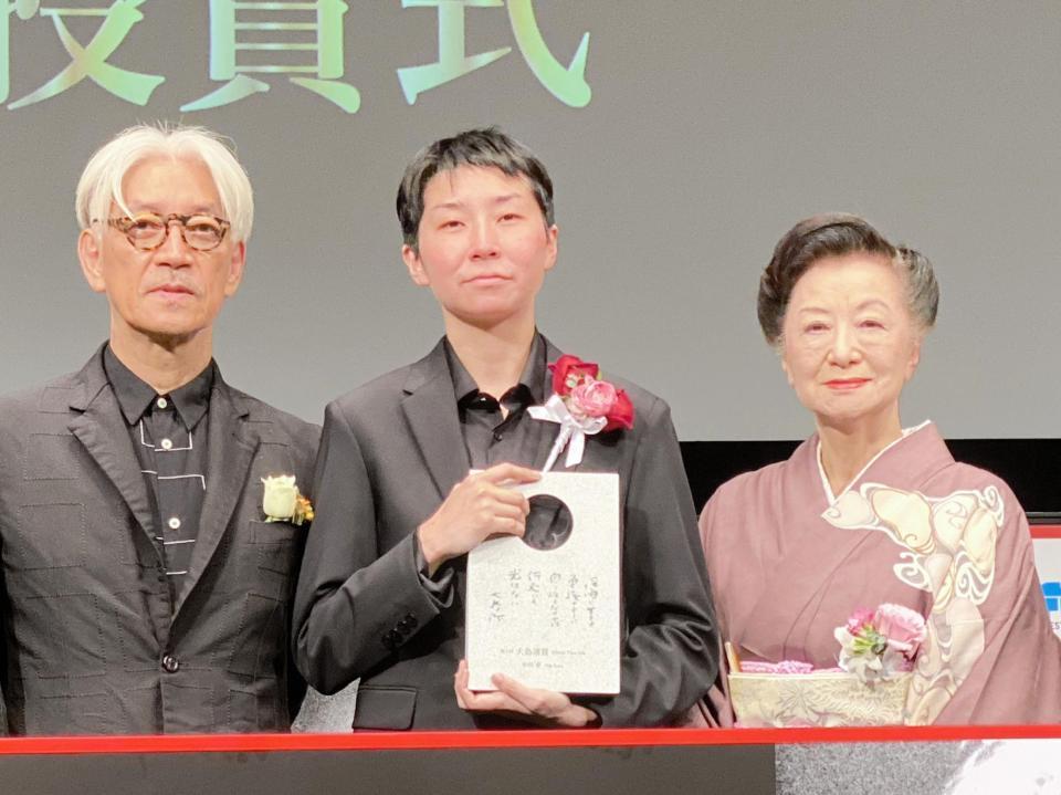 受賞した小田香監督（中）に賛辞を送った坂本龍一と小山明子＝東京・丸の内