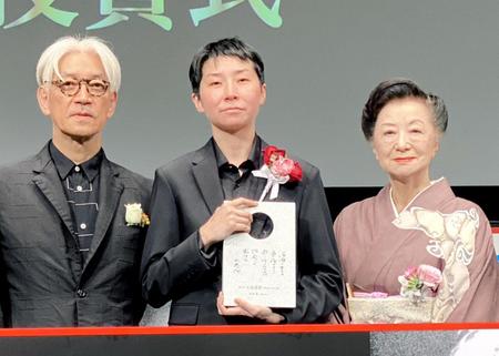 　受賞した小田香監督（中）に賛辞を送った坂本龍一（左）と小山明子＝東京・丸の内