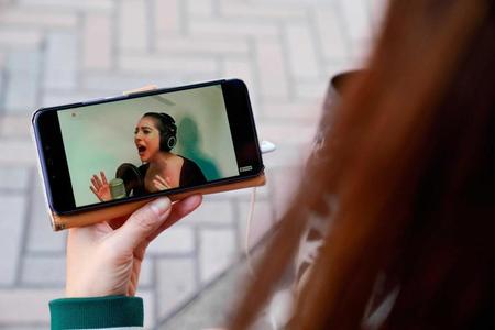 レディー・ガガのパフォーマンスをスマートフォンで視聴する女性＝東京都（ゲッティ＝共同）